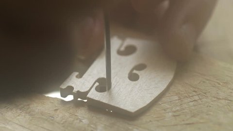 A luthier makes violin bridge. Close up. Violin master hands