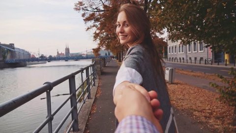 POINT OF VIEW: Young Woman Pulling her Boyfriend Through Autumn City Street. SLOW MOTION 120 fps. POV: Happy Girlfriend Makes her Man to Follow Her to the City Bridge. 