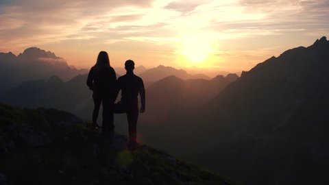 Aerial, edited - Raising above hiking couple watching beautiful sunset in the mountains