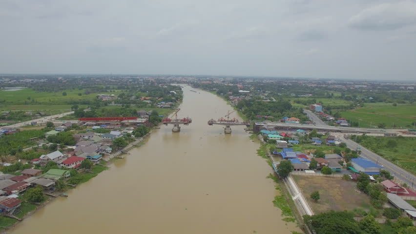 Aerial footage of under contruction bridge across the Chao Phraya River.