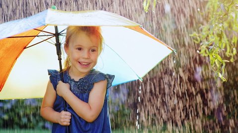 Carefree girl three years under the umbrella of color. Hiding from the rain