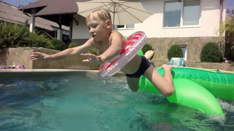 Moving the camera. Spray flew at the camera. Slow motion. Kids Inflatable Giant Rideable Turtle. Boy jumping in the pool. Underwater view.