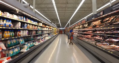MONTREAL, CANADA - AUGUST 2016: Shopping Inside Walmart - Professional Steadicam Shot (Refrigerated Dairy Products & Meats - Milk, Chicken, Beef, Bacon & Orange Juice)