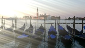 Parked gondolas on Piazza San Marco and The Doge's Palace embankment with the bell tower of the Saint Giorgio Maggiore Church on background in slow motion.