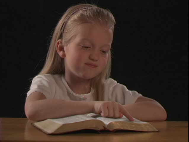 A young girl reads the Bible.