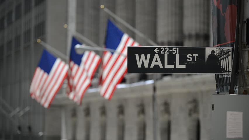 Wall Street sign with American flags purposely blurred in background, HD video