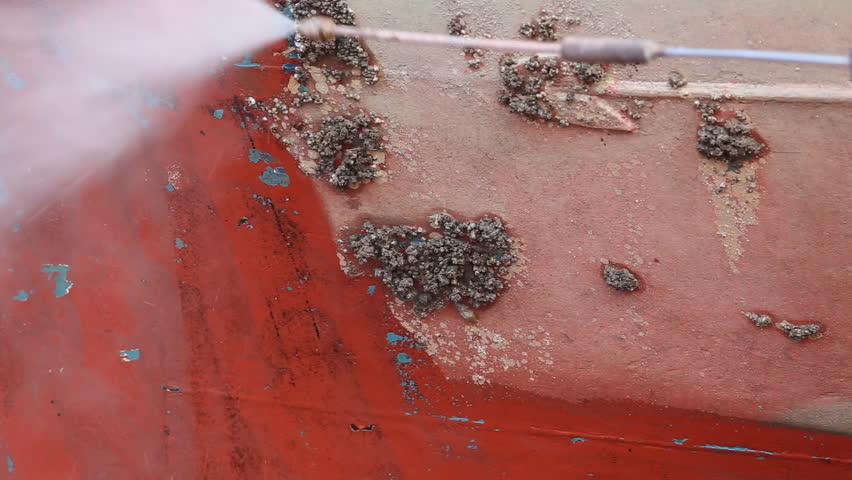 A man working on pressure washer to cleaning boat hull barnacles antifouling and seaweed at the harbor