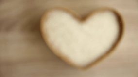 Rice with heart shaped in basket on wooden background.
