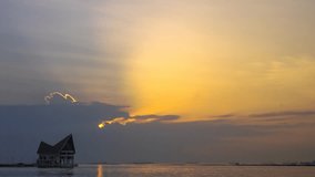 4K time lapse of sunset sky at sea with silhouette of building 