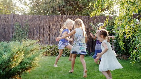 Children playing in the summer garden. Grupa children have fun under water jets or rain