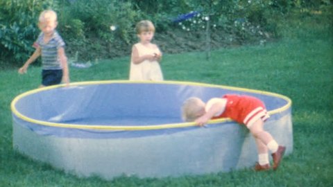 AKRON, OHIO, JUNE, 1967: A cute little blond haired boy and his friends have fun playing with a toy boat in the kiddie pool in the summer of 1967.