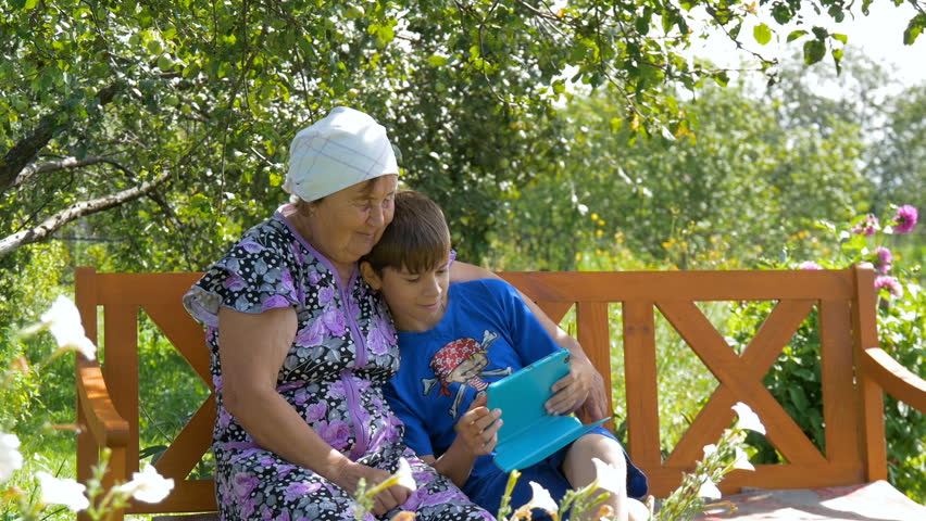 Boy teaches her grandmother how to use the tablet.