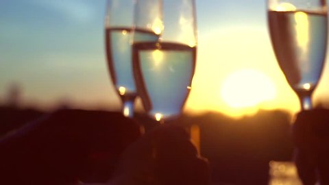 Group of people toasting and drinking champagne on the restaurant terrace over sunset. Celebrating. Glasses with Sparkling Champagne over nature Background. Resort. Slow motion full hd 1080p