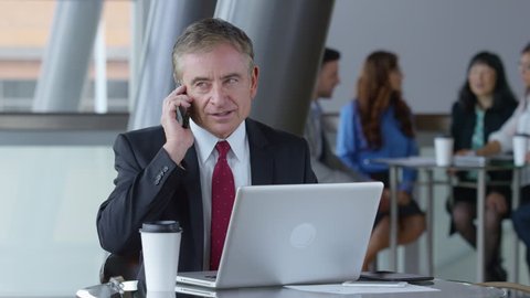 Mature businessman using cell phone in office lobby