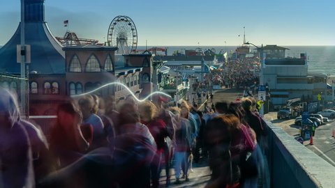 Santa Monica Pier, Los Angeles. People entering the crowded Santa Monica Pier at sunset. Timelapse. California, United States.