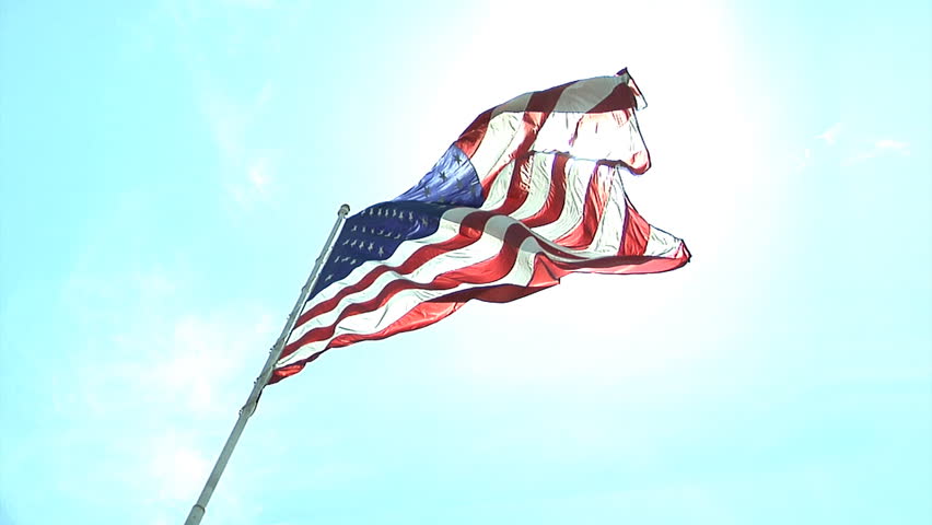HD clip of the American flag wavering with bright a bright blue sky as