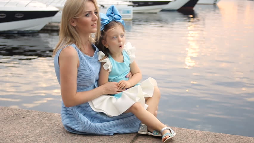 little girl three years sitting on the lap of the mother with long blond hair
