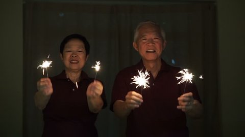 Asian senior elder couple playing firework, sparklers, fire cracker at night. Concept celebrating life วิดีโอสต็อก