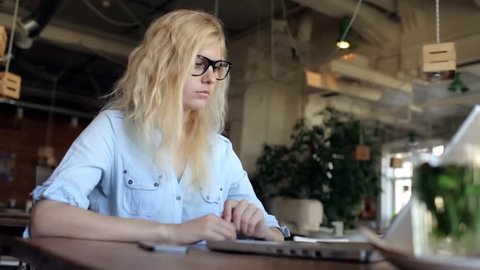 Girl With Glasses Enters Credit Card Information Into a Laptop in a Cafe. Online Shopping
