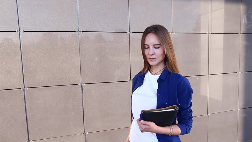 Woman Girl Lady Portrait Looking Camera Walking and Shows Thumbs up Down Like Dislike. Young Beautiful Student Business Female With Long Hair on the Background Building.