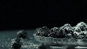 Overview of a fresh blueberry heap powdered with sugar on the glass plate
