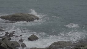 Dramatic water waves splashing and crashing against rocks. slow motion video of waves breaking near a rocky shore