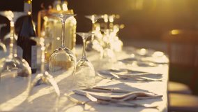 Laying out of the elegant dinner table for wedding celebration. Outside shooting. No people around. Only glasses and wine are glancing on the sunshine. Camera stabilizer shot. - Powered by Shutterstock - Get 15% off with code: PIKWIZARD15