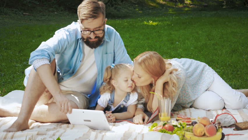 family portrait of happy girl and mom and dad having fun on the grass in sunny summer day