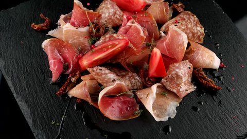 Restaurant meat platter (ham, salami, bacon) on the black stone tray