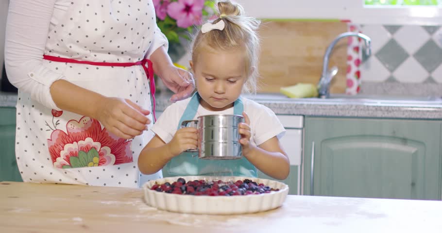 Mother teaching her cute little daughter to bake