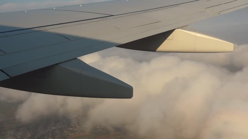 Airplane flying over clouds and village. Filmed from  commercial jet airplane