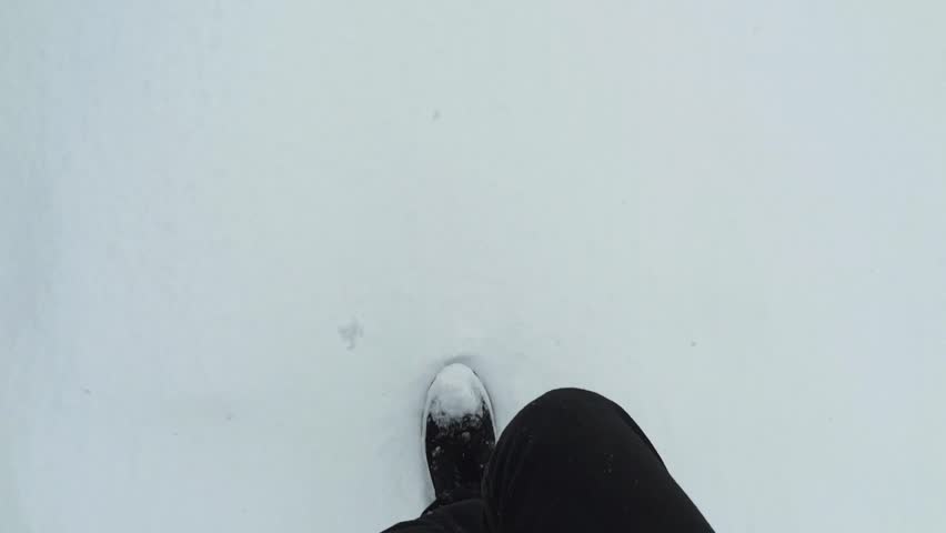 Point of view of feet walking on snow.