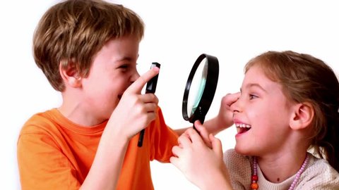 Two kids boy and girl play with magnifying glass isolated on white background
