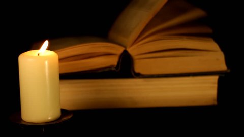 Candle blazes on background of the book
