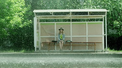Girl sitting at the bus stop in the rain.  Shot on RED EPIC Cinema Camera in slow motion.