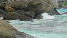 Turquoise rolling wave slamming on the rocks of the coastline, slow motion. Best use for relaxing video
