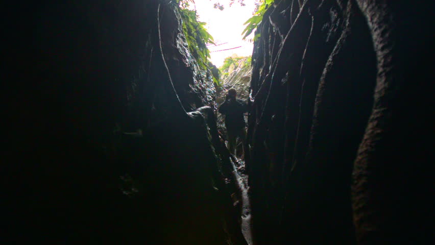 man stands in deep dark narrow canyon and photos against bright backlight in national park in Vietnam