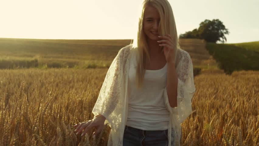 Smiling blond girl wonders cross the field of wheat, woman of fashion, the sun is shining. Slow motion, stabilizer shots. Happiness, love, youth. | Shutterstock HD Video #19097602