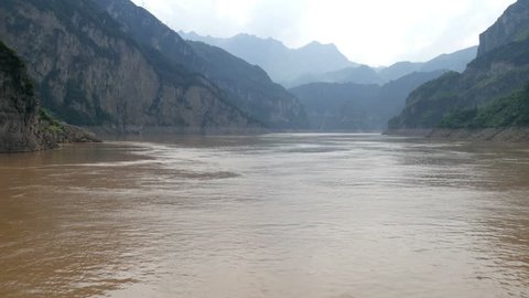 China Yangtze river above the Three Gorges dam, pan across the mountain skyline river center with steep rocky cliffs & distant mountains