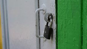 Closeup of male hands quickly open a metal padlock with a key on an old wooden door and a person goes through doorway