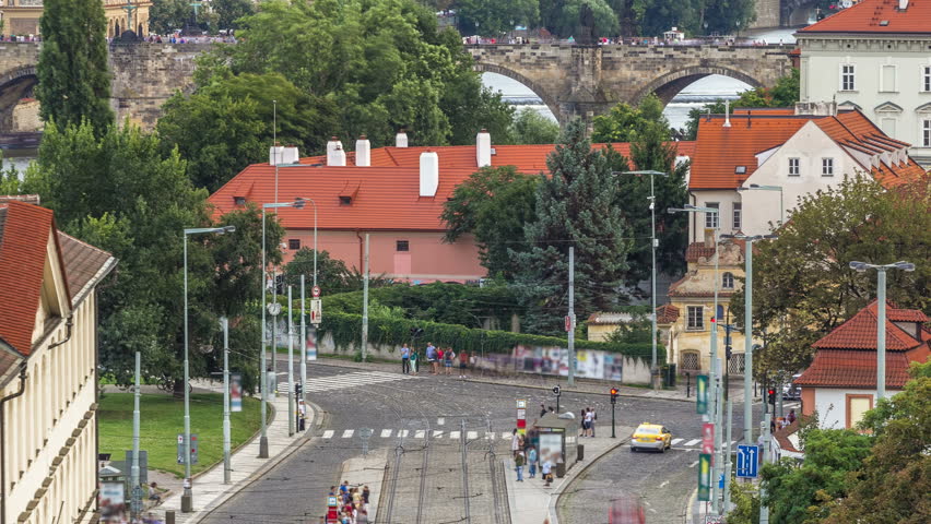 Scenic summer aerial view of the Lesser Town architecture and Charles Bridge over Vltava river timelapse before sunset in Praha. Prague, Czech Republic. Top view of Malostranska tram stop