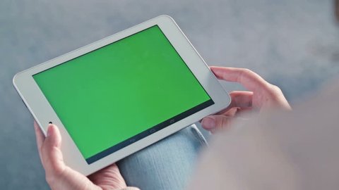 Woman looking at tablet with green screen. Close up shot of woman's hands with pad