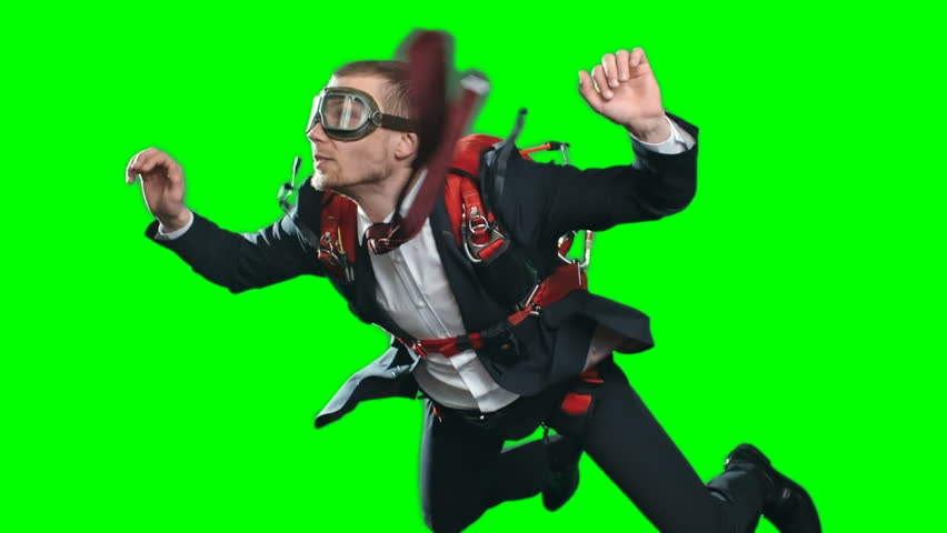 Concept of taking risks in business, worried man with parachute wearing formal suit and aviator mask in free fall looking down and moving up out of frame, chroma key green screen background