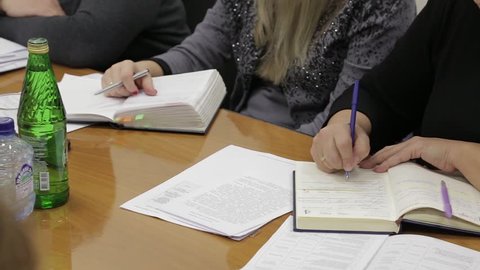 Two women write in notebooks