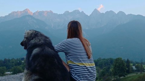 A gril looking at mauntains wiht her dog in slow motion