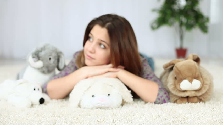Smiling teenagers lying on the floor with plush rabbit 