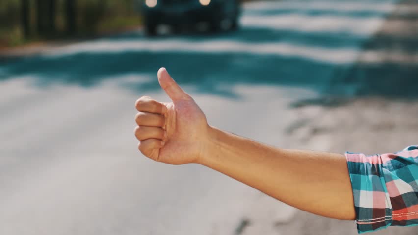 Young boy hitchhiking at road in summer day. Thumb up. Transportation. Cars. Countryside.