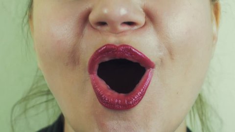 Woman with red pomade emphatically sing song in front camera. Mouth. White teeth. Close up