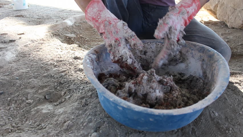 Mixing Mortar. A worker is mixing mortar by his hands.