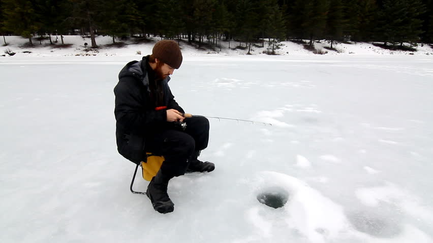 Man ice fishing on frozen lake
